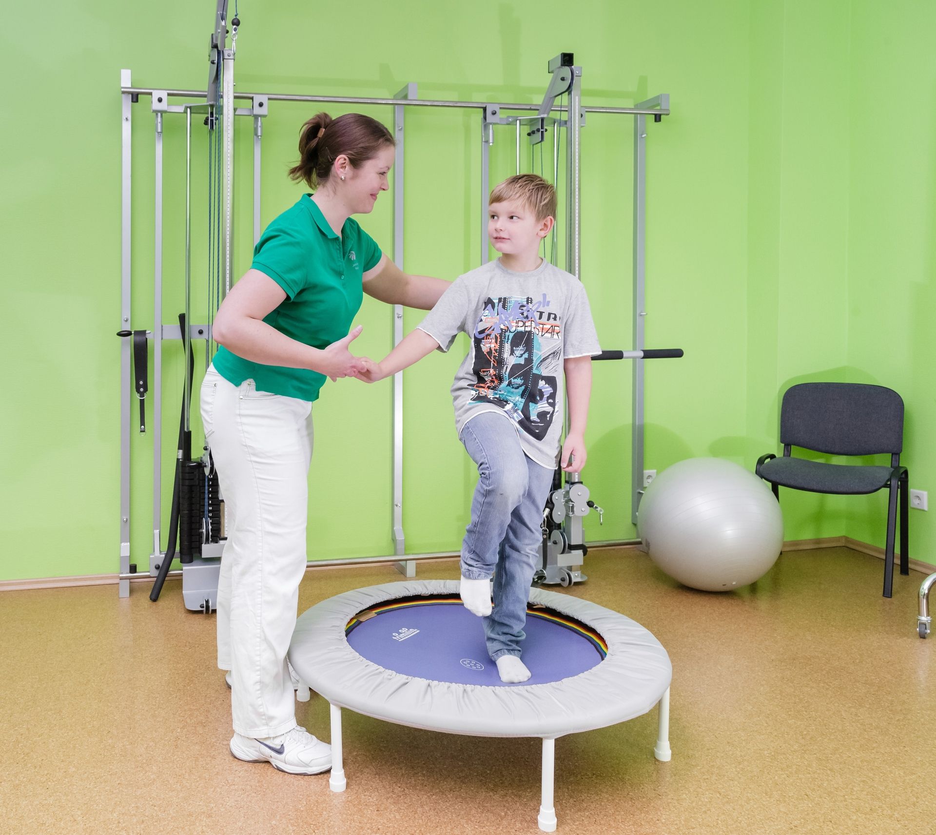 Klassische Krankengymnastik mit einem Kind und der Verwendung eines Trampolins